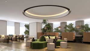 A modern lounge area with a circular ceiling light, seating arrangements, and potted plants. - Hilton Garden Inn Chongqing Yubei Central Park (Chongqing)