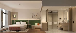 Une chambre d’hôtel moderne avec un grand lit, un petit canapé, une table de chevet, un miroir et une salle de bain équipée d’un lavabo et d’un miroir.