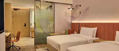 Habitación de hotel con dos camas, un escritorio, una silla y una puerta corredera que da a otra habitación.