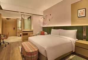 Une chambre d’hôtel moderne équipée d’un grand lit, d’un bureau, d’une chaise, d’un banc et d’un miroir.