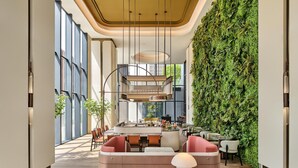 A modern interior with a central seating area, a staircase, and a green wall. - Hilton Garden Inn Chongqing Yubei Central Park (Chongqing)