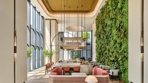 A modern interior with a central seating area, a staircase, and a green wall. - Hilton Garden Inn Chongqing Yubei Central Park (Chongqing)