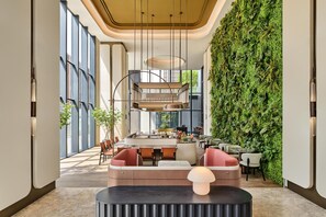 A modern interior with a central seating area, a staircase, and a green wall. - Hilton Garden Inn Chongqing Yubei Central Park (Chongqing)