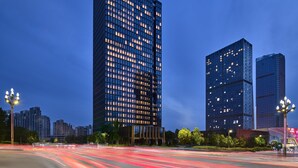 A modern high-rise building with a grid of windows and a red top. - Hilton Garden Inn Chongqing Yubei Central Park (Chongqing)