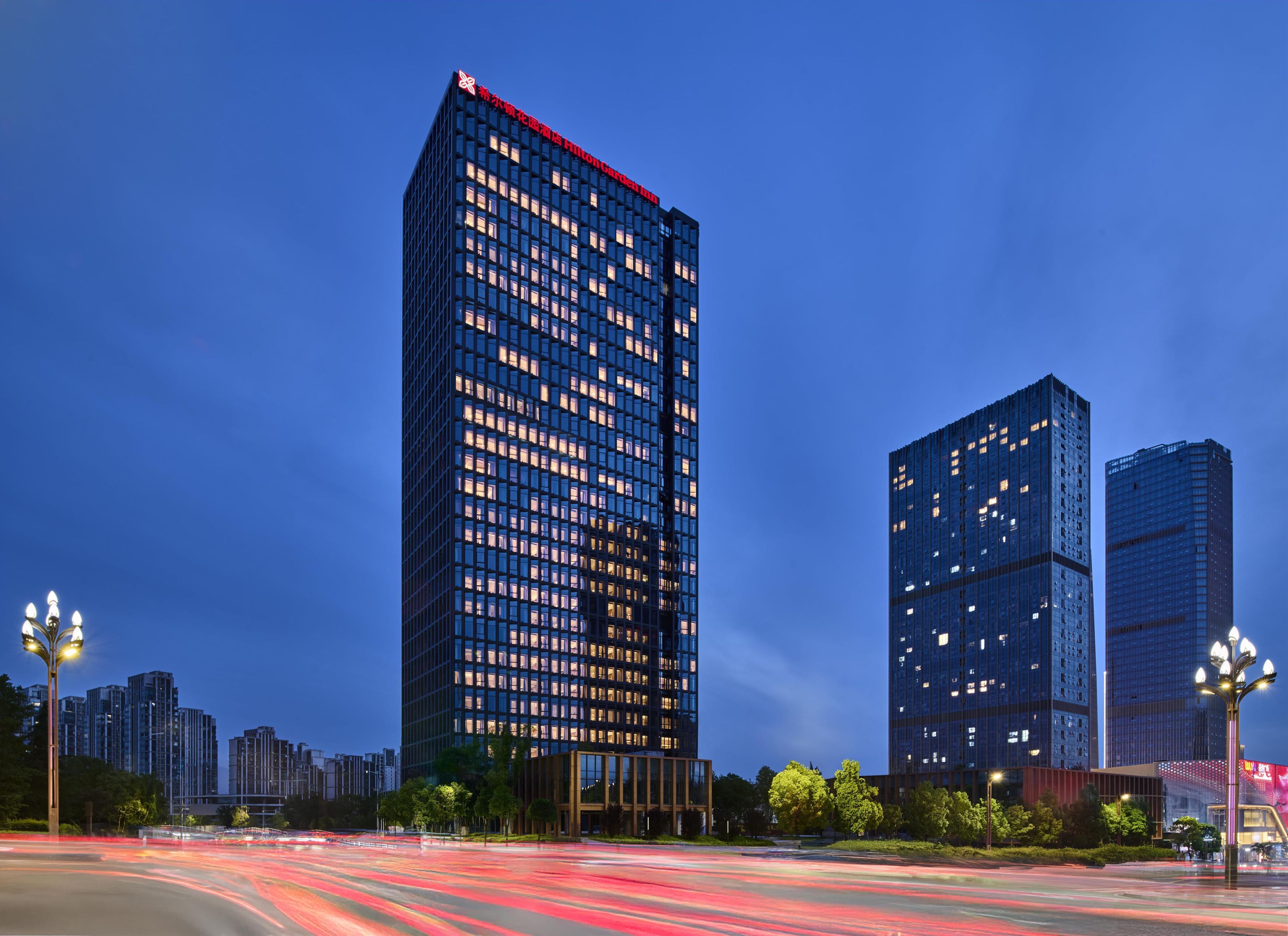 Un moderno edificio de gran altura con una fachada de ventanas enrejadas y una parte superior roja.