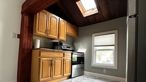 Una cocina con armarios de madera, un refrigerador de acero inoxidable y un tragaluz.