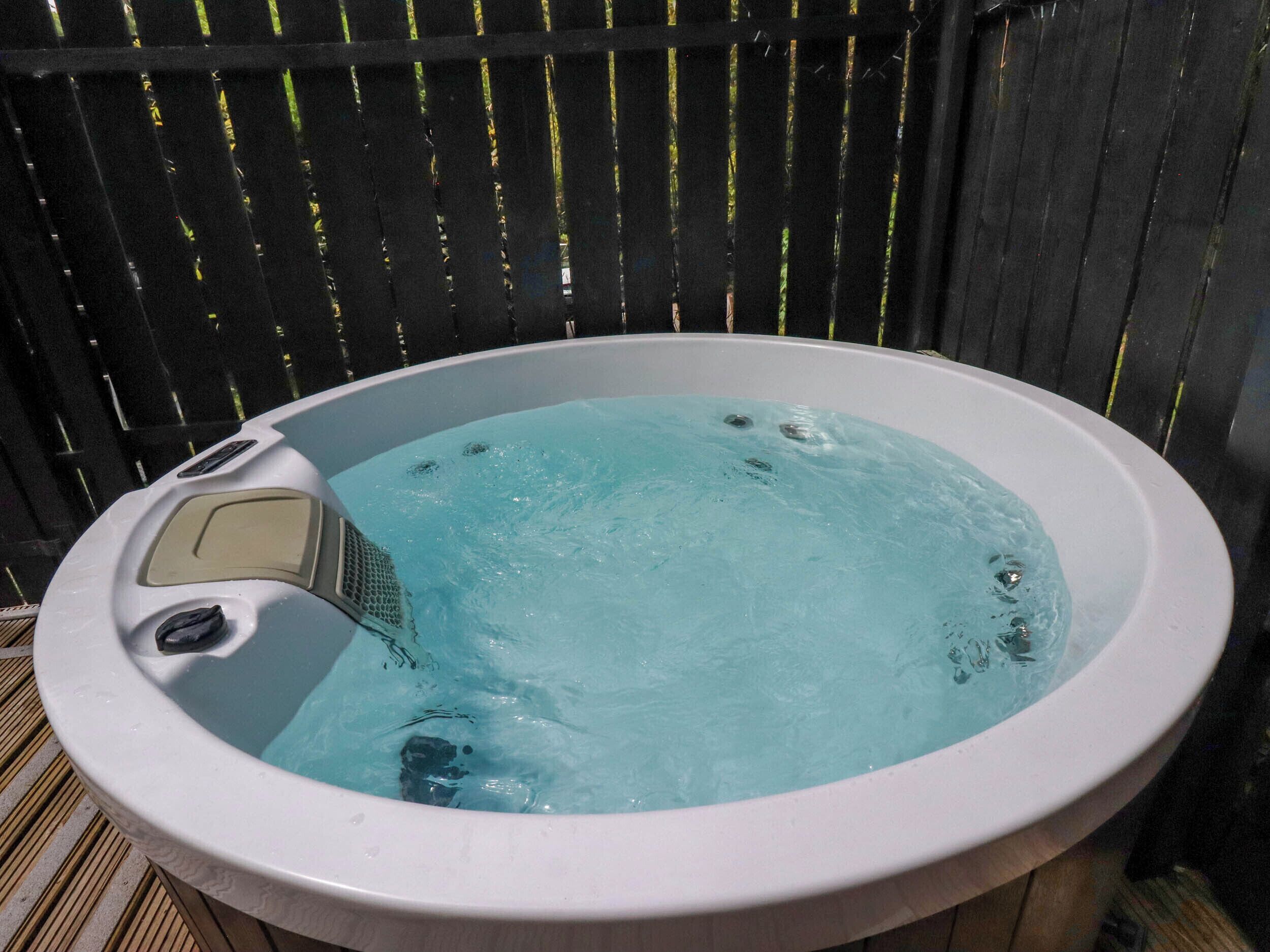 Ein Whirlpool mit Bedienfeld, umgeben von einem Holenzaun.