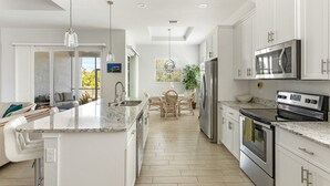 Una cocina moderna con armarios blancos, electrodomésticos de acero inoxidable y encimera de mármol.