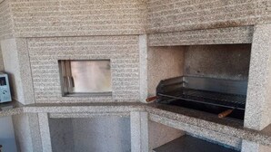 A concrete-built outdoor kitchen with a grill and a small window. - Casa do Penedo Gordo (Fafe)