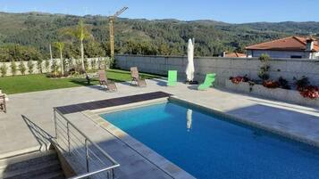 Ein Schwimmbecken mit Blick auf Hügel und Windkraftanlagen im Hintergrund.