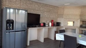 A compact kitchen with a built-in refrigerator, a microwave, a coffee maker, and a flat-screen TV. - Casa do Penedo Gordo (Fafe)