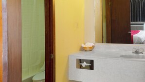 Een badkamer met een witte wastafel, een spiegel en een houten deur.