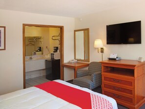 Comfortable room with a bed, dresser, chair, desk, and flat-screen TV.