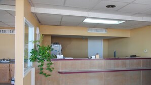 Een receptiezone met een balie, een koelkast, een plant en een raam.
