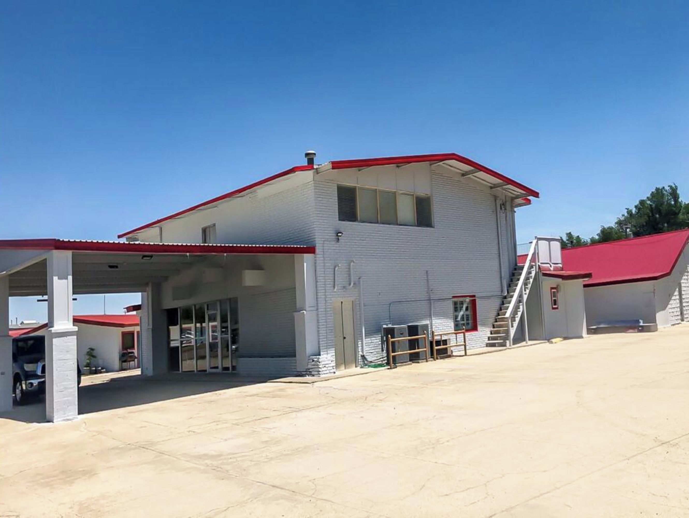 A gas station with a covered fuel pump area, a single-story building, and a red roof.