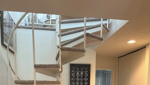 A spiral staircase with a textured handrail and a geometric wall panel.