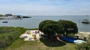 A beach with a dock, boats, and a grassy area with outdoor furniture.