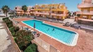 A swimming pool with sun loungers and a view of yellow buildings. - Balcony Pool Royal Cabanas Golf 18 (Tavira)