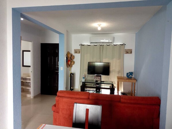 A living room with a red sofa, a television, and a ceiling fan.