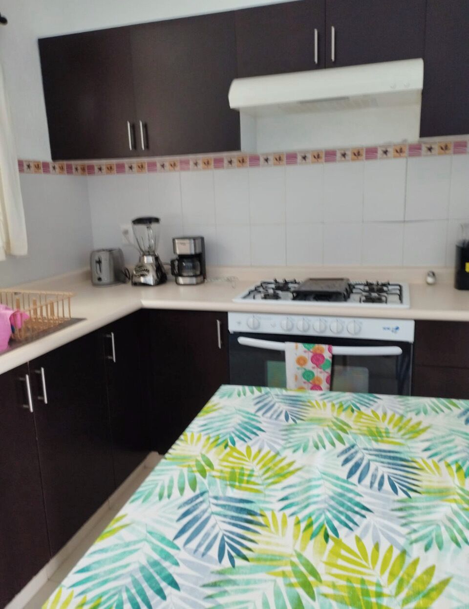 Een keuken met donkere kastjes, een gasfornuis, een koffiezetapparaat en een broodrooster.