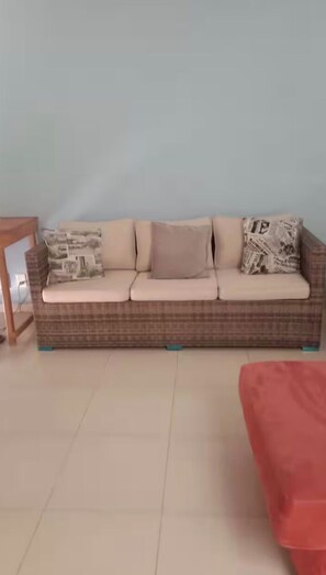 A room with a brown patterned sofa against a light blue wall, a small wooden side table, and a red piece of furniture.