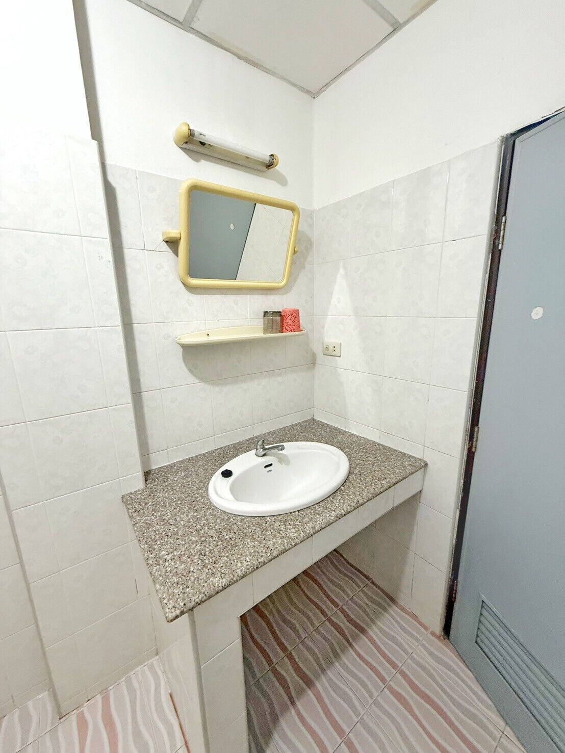 A small bathroom with a white sink, a mirror, and a towel rack.