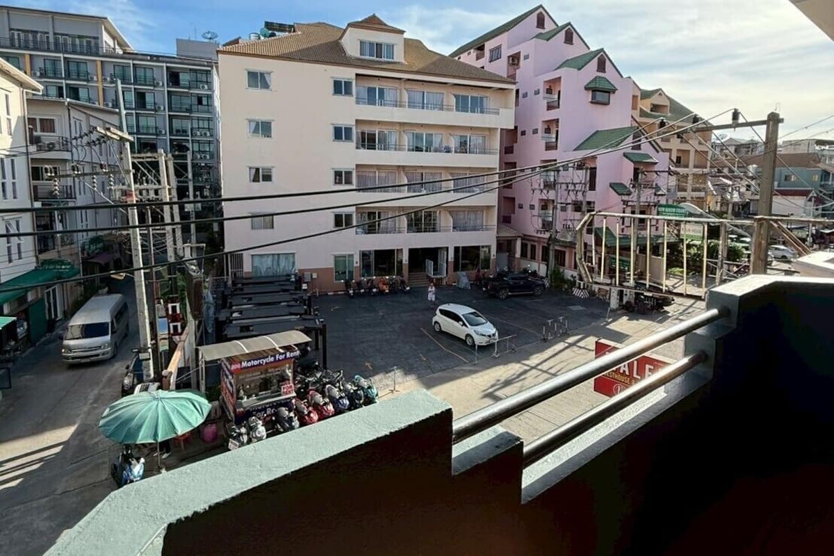 Un edificio de varios pisos con balcones, estacionamiento y vista a la calle.