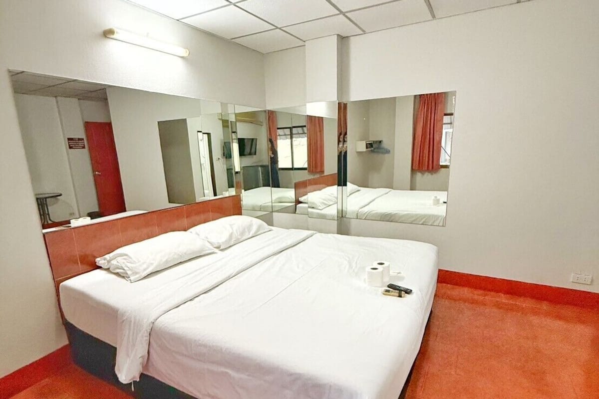 Una habitación de hotel con una cama grande, un espejo y una alfombra roja.