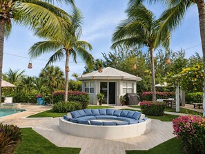A circular outdoor seating area with a pool and a small building in the center.