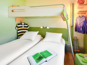 Une chambre d’hôtel avec deux lits simples, un lit superposé, un mur vert et un skateboard appuyé contre le mur.