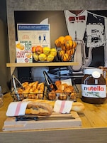 A buffet table with croissants, bread, and a Nutella jar.