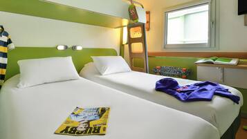 Une chambre d’hôtel avec deux lits, une échelle, une fenêtre et un magazine posé sur l’un des lits.