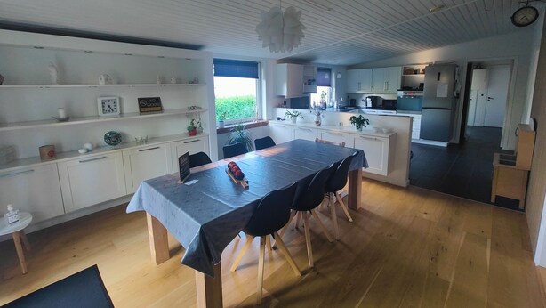 Una cocina moderna con armarios blancos, una mesa de comedor con sillas y vistas al exterior.