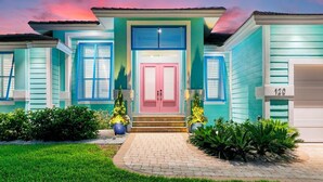 Een huis met twee verdiepingen, een roze deur, blauwe luiken en het getal '120' aan de rechterkant.