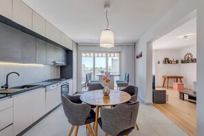 Cozinha moderna com área de refeições, janelas amplas e vista para a cidade.
