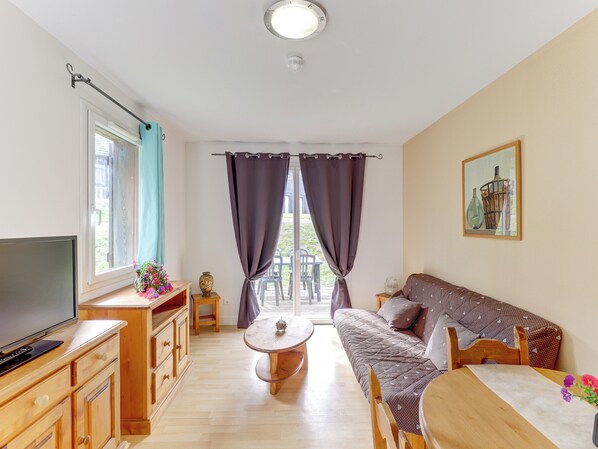 A cozy living room with a sofa, TV, wooden cabinets, and a dining table. - Residence Le Domaine Du Bosquet (Miremont)