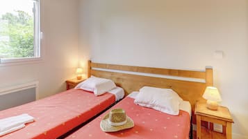 A bedroom with two beds, a window, and a nightstand with a lamp.