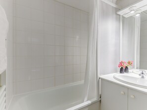 Un baño con bañera, lavamanos y espejo.