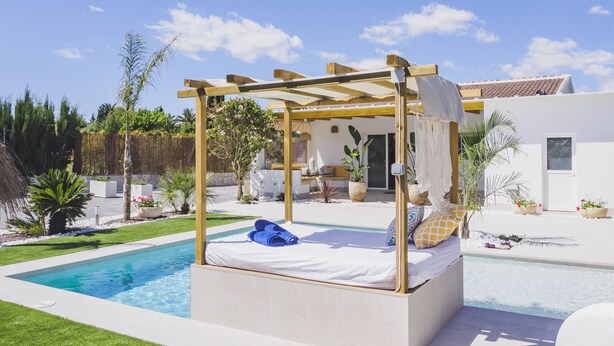 Een moderne buiten slaapkamer met een zwembad, een pergola en een terras met zitplaatsen.