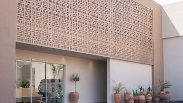 Een modern gebouw met een geometrisch gevelontwerp, grote ramen en potplanten.