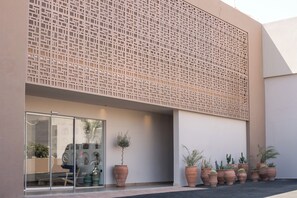 Een modern gebouw met een geometrisch gevelontwerp, grote ramen en potplanten.