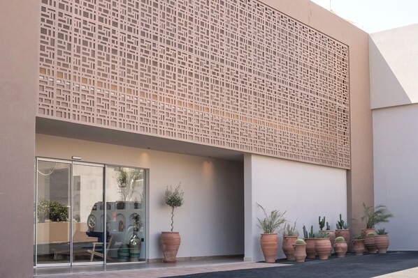 Un edificio moderno con fachada geométrica, ventanas amplias y plantas en macetas.