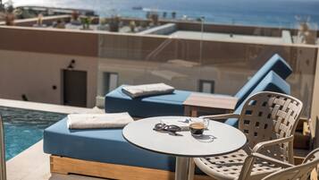 Un balcon avec une piscine, une table avec une boisson et une paire de lunettes.