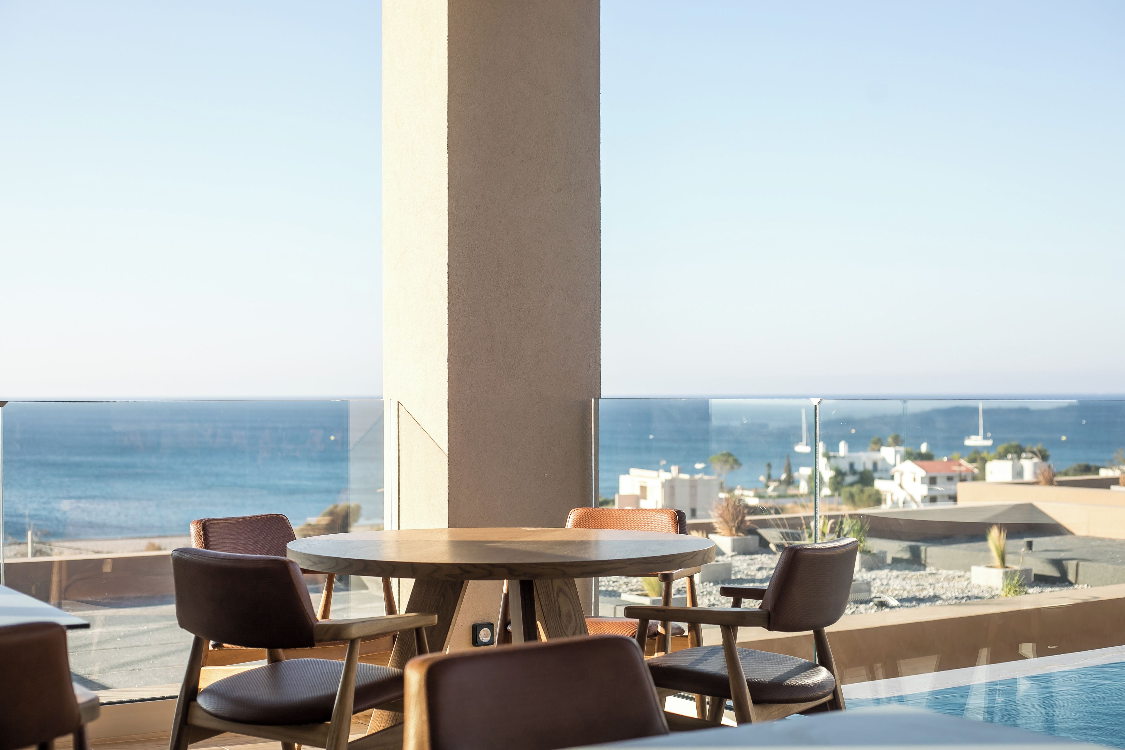 Une terrasse sur le toit avec une piscine, des chaises et une table, d’où l’on a une vue sur l’océan.