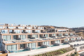 A multi-story hotel with balconies, swimming pools, and a hilly landscape in the background. - Este Elegant Suites and Villas (Rhodes)