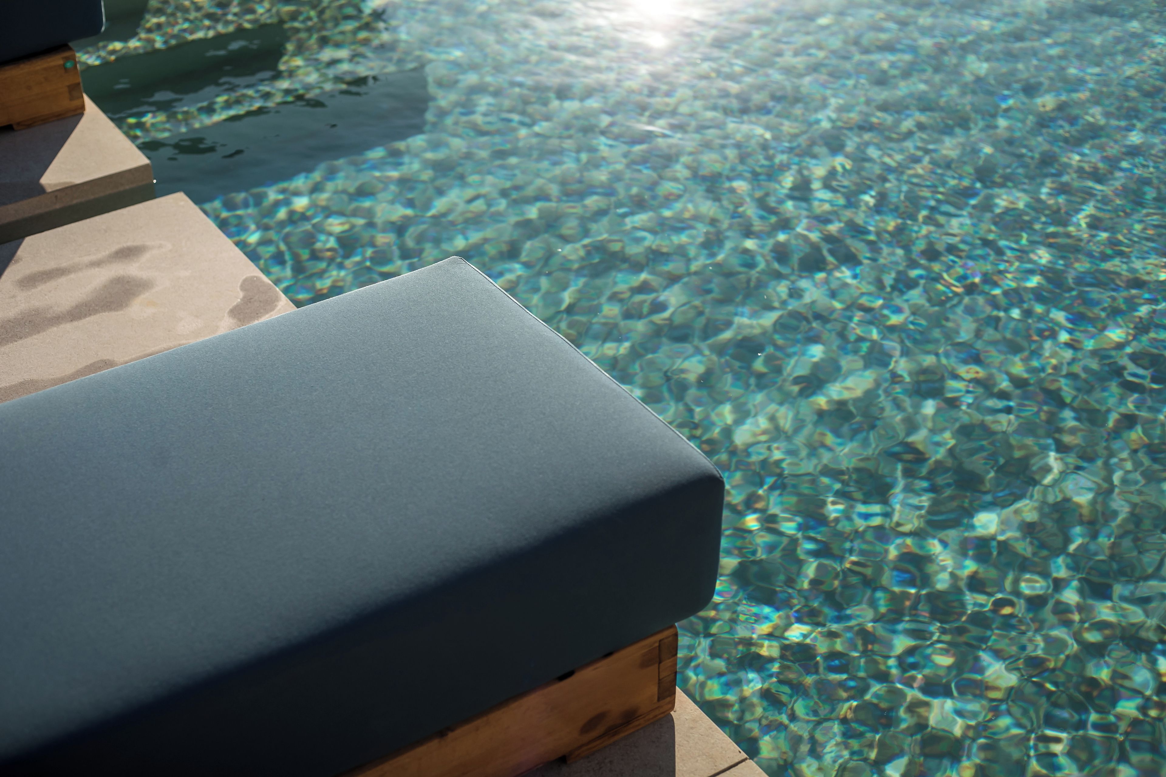 A clear pool with a wooden deck and lounge chairs.