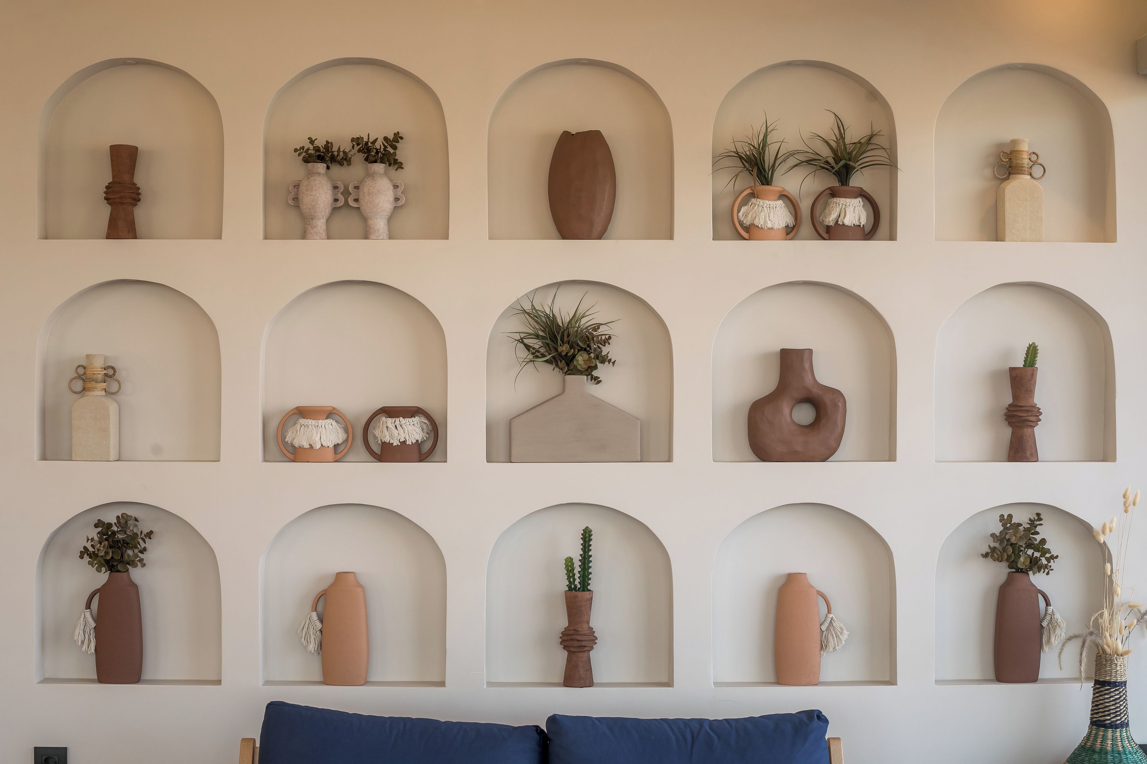 A wall with multiple arched niches containing various decorative items.
