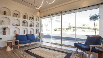 Una sala de estar moderna con un sofá, sillas, un tapete grande y una pared de estantes con objetos decorativos.
