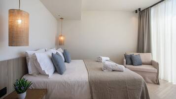 Una habitación de hotel moderna con una cama grande, un sofá, una lámpara colgante y una planta en maceta.