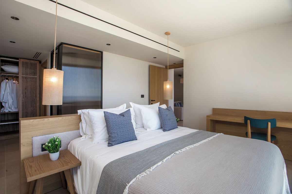 Un dormitorio moderno con una cama grande, mesitas de noche, una mesita auxiliar, un escritorio y una silla.